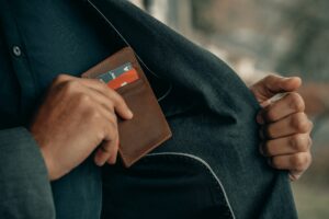 La imagen destacada de este texto sobre ventajas de las tarjetas de crédito es una fotografía en la que hemos como un tarjetero color café es guardado al interior del saco que parece portar un hombre.