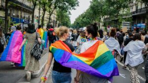 Como imagen destacada para este texto sobre sobre la inclusión LGBTQ+ en 10 empresas de México, hemos seleccionado una imagen en la que se diferentes personas caminando en la calle. Varias de ellas llevan amarradas a la espalda banderas de la diversidad sexual.