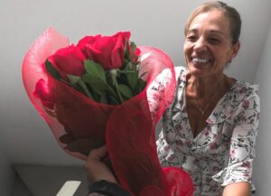 La imagen destacada para este texto sobre la historia detrás del Día de las Madres en México es una fotografía a una mujer que aparece de frente subiendo unas escaleras y recibiendo un ramo de rosas rojas de un brazo extendido.