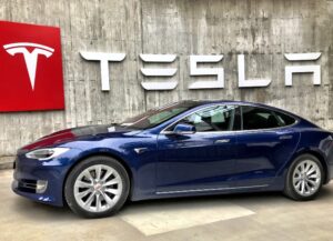 Para este texto sobre la caída de case 7% de las acciones de Tesla, empresa fundada por el multimillonario Elon Musk, tenemos como imagen destacada una fotografía en la que se ve un automóvil de la firma, abajo del logo de esta.