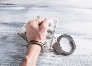 Como imagen destacada para este texto sobre que la ley de Suiza condenó a Credit Suisse por lavado de dinero, tenemos una fotografía de una mano con esposa, en posición de puño sobre tres billetes.