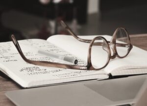 La imagen destacada para este texto sobre las mejores y peores afores es una fotografía que muestra unas gafas sobre una libreta en la que se ve que han escrito mucho.