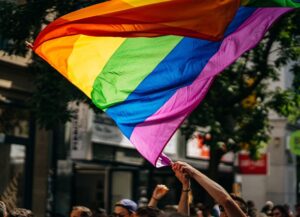 Como imagen destacada de este texto sobre el origen de junio como el mes del pride u orgullo LGBTIQ+, tenemos una fotografía de una marcha de la diversidad sexual en la que destaca la bandera del arcoíris.