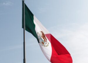 Como imagen destacada para este texto sobre que el presidente Andrés Manuel López Obrador (AMLO) dijo que sus pares de Estados Unidos (EU) y Canadá, visitarán México para discutir el T-MEC, tenemos una fotografía de la bandera de México con el cielo despejado de fondo.