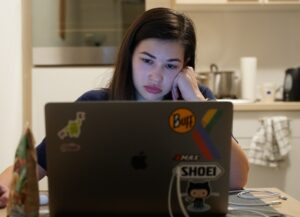 Para este texto sobre qué hacer para evitar llegar al punto de 'burnout' tenemos una imagen destacada en la que vemos a una mujer con expresión de pesimismo, sentada frente a su computadora portátil.