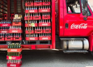 Para este texto sobre que Coca-Cola Femsa aumentará sus precios, tenemos una imagen destacada de un camión repartidor de esta empresa, donde vemos las botellas de sus productos.