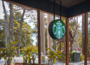 Como imagen destacada para este texto titulado: Starbucks quiere pausar elecciones sindicales, tenemos una fotografía en la que vemos el logo de la cafetería en un aéreo abierta de un local.