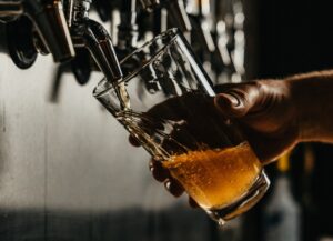 Como imagen destacada para nuestro texto titulado: ¿Freno a la producción de cerveza en el norte del país?, tenemos una fotografía de una mano que sostiene un vaso que está siendo llenado de cerveza por un dispensador.