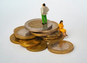 Como imagen destacada de este texto para entender una recesión tenemos una fotografía en la que vemos dos figuras humanas a escala menor sobre una pila de monedas.