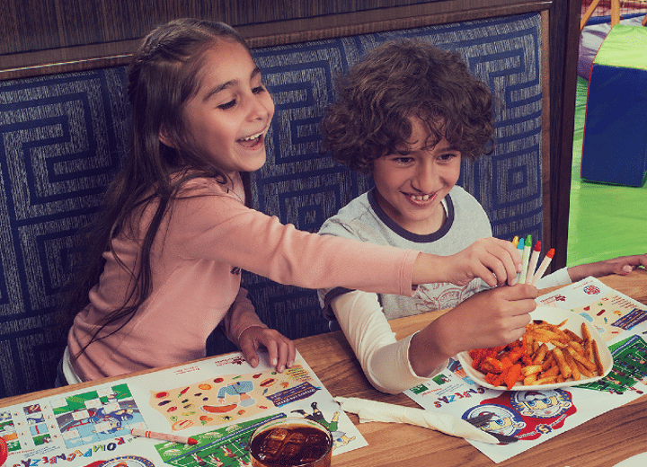 Como imagen interna tenemos una fotografía de una niña y un niño coloreando sobre la mesa de Boston's Pizza, disfrutando de su modalidad como restaurante familiar (restaurant).