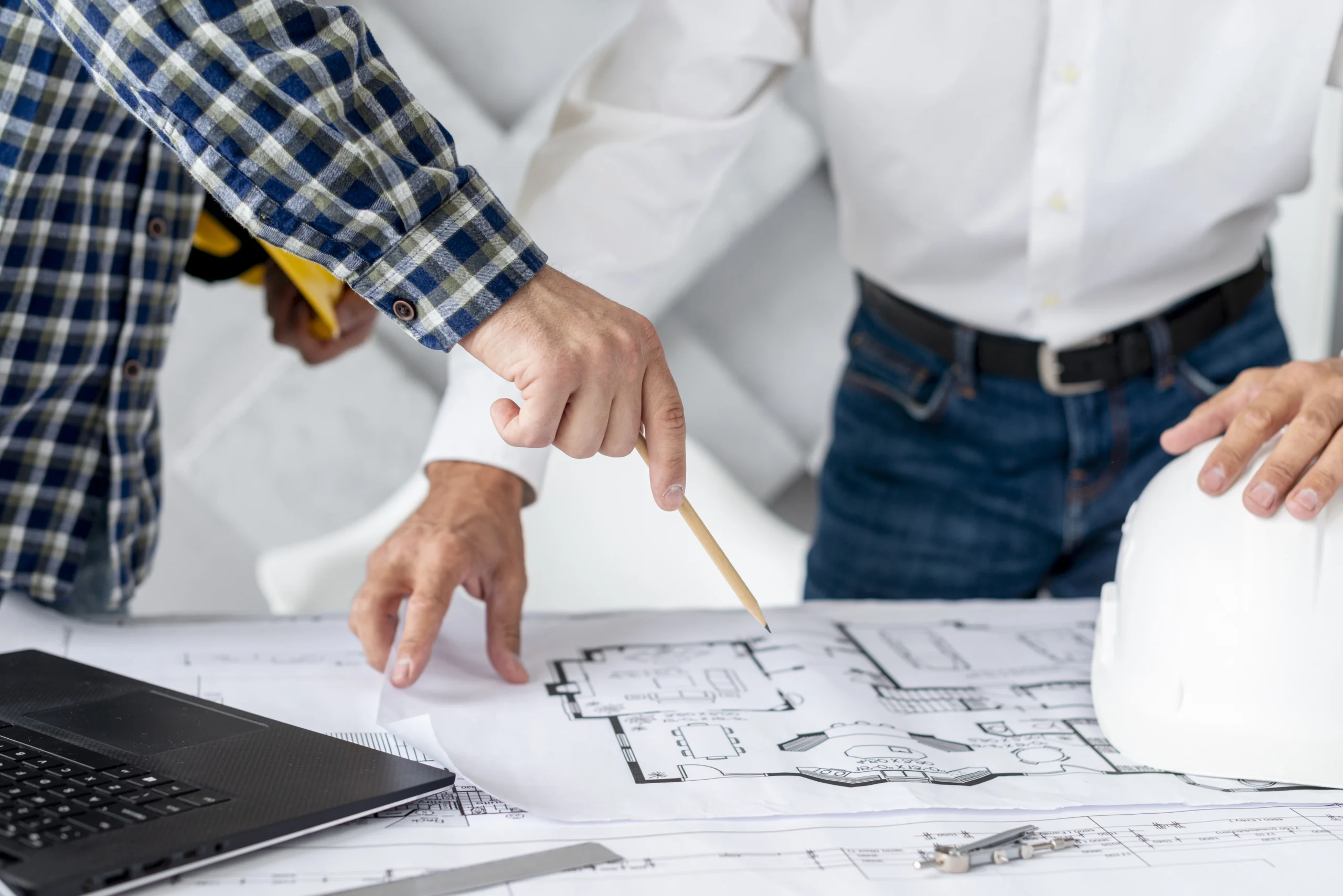 Como imagen destacada para este texto en el que hablamos del Día del Arquitecto, tenemos una fotografía ilustrativa de una gráfica que representa un plano y una mano sosteniendo un lápiz.