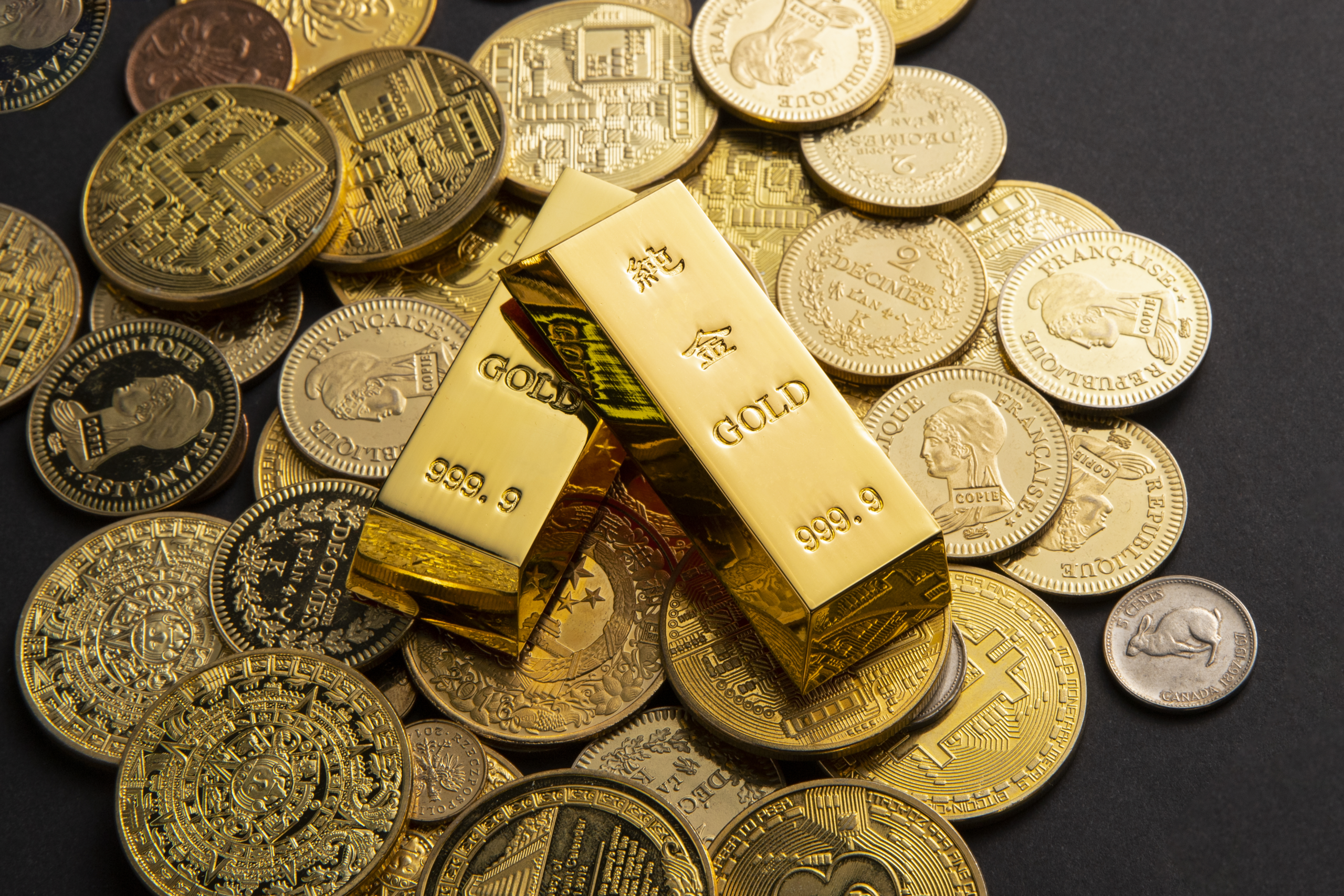 Como imagen destacada para este texto en el que hablamos de invertir en oro, tenemos una fotografía ilustrativa de monedas y lingotes de oro.