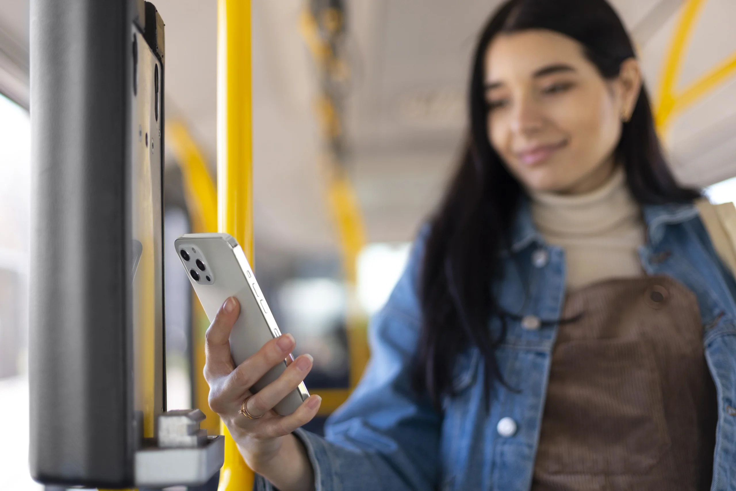 Como imagen destacada para este texto en el que hablamos del transporte público, tenemos una fotografía de una mujer con un teléfono en la mano utilizando el transporte público.