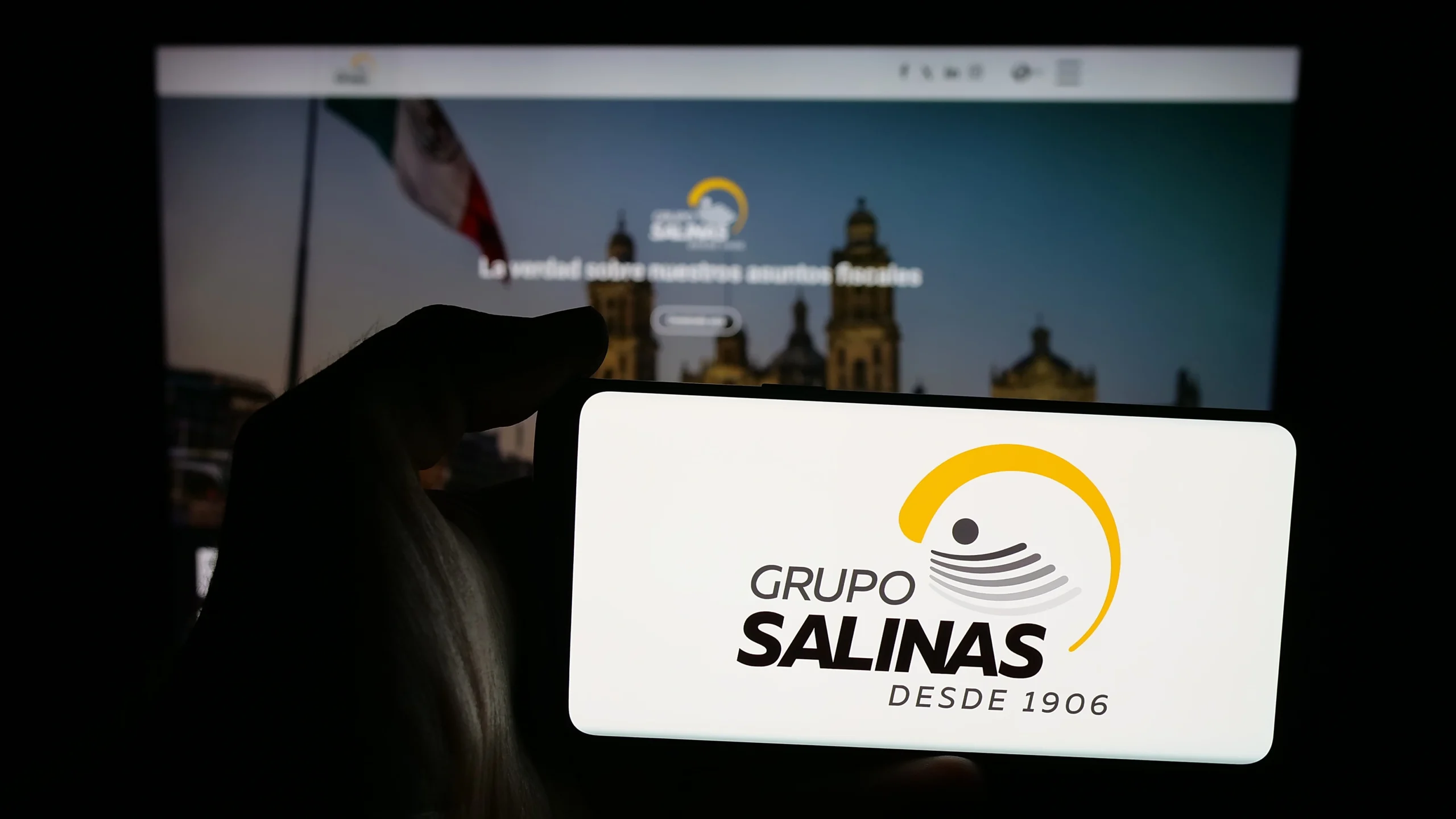 Como imagen destacada de esta entrada donde hablamos de las deudas de Grupo Salinas con el SAT, tenemos una imágen ilustrativa del logo de Grupo Salina en un celular frente a una laptop. 