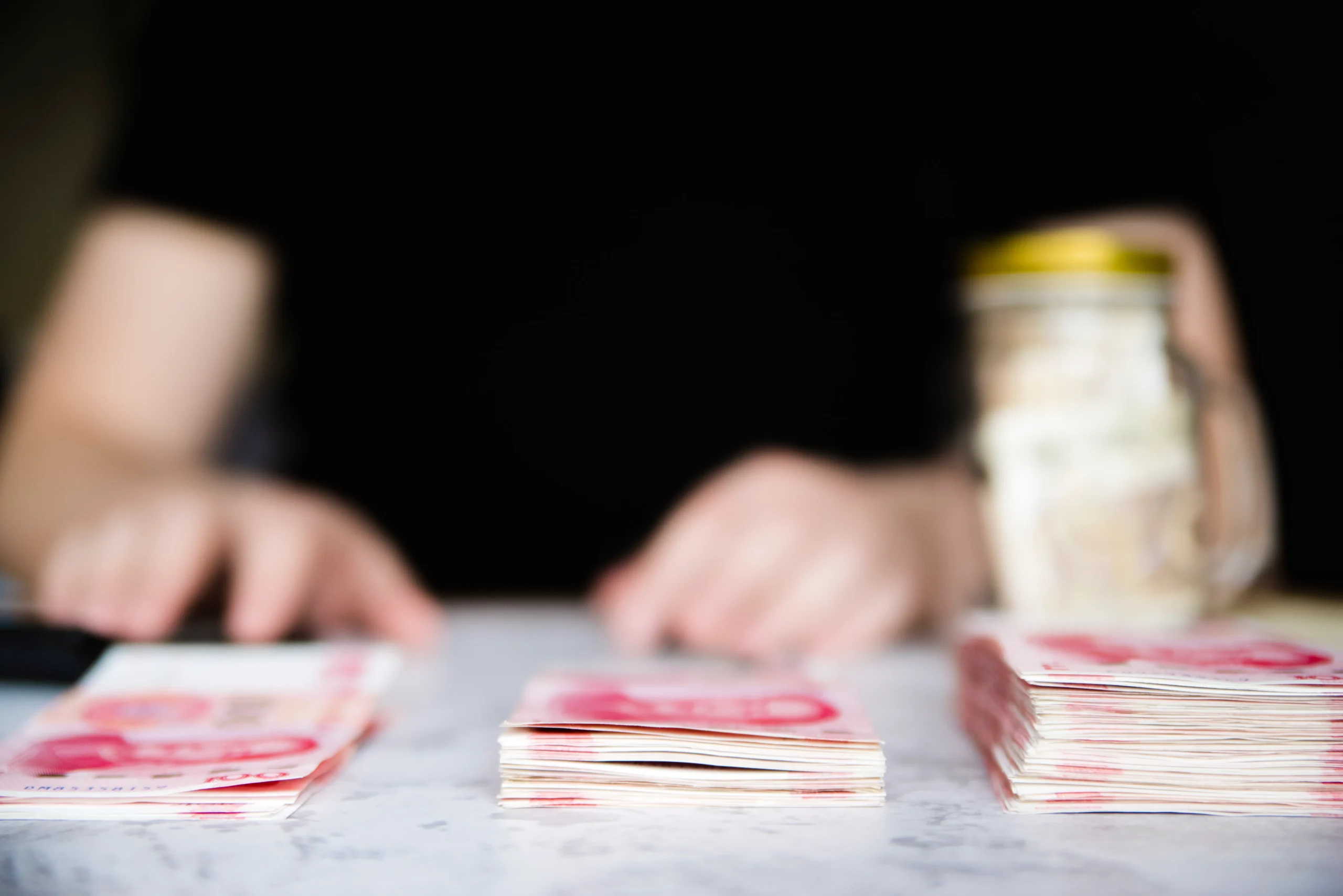 Como imagen destacada para este texto en el que hablamos de cómo administrar el aguinaldo, tenemos una imágen ilustrativa de una persona dividiendo dinero frente a una alcancía.